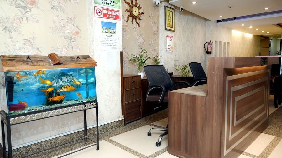 A hotel reception desk with a decorative fish tank, comfortable seating, and informative signs on the walls - Hotel Diamond Inn, Chandigarh