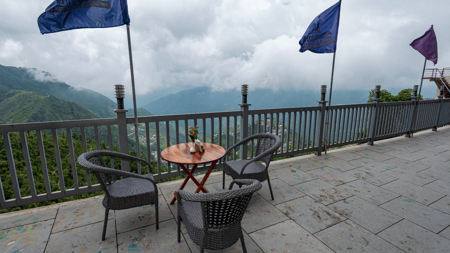 Outdoor dining area with tables and chairs overlooking misty mountains at MV Acosta, Mussoorie.