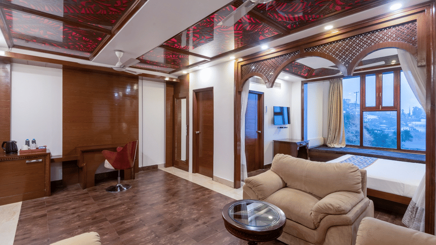 Spacious suite with plush sofa chairs, writing desk, and double bed at The Solitaire Resort, offering a blend of comfort and elegance with modern amenities.