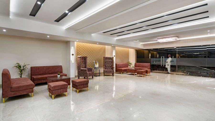 A spacious hotel lobby with brown cushioned seating, wooden tables, and a polished white floor. – Clarks Inn Suites, Near Taj Mahal