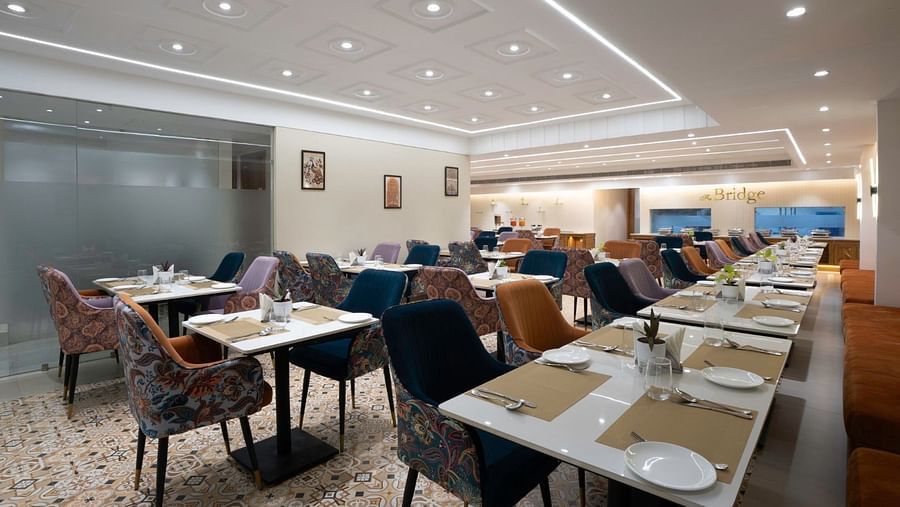 A modern restaurant with white marble tables, cushioned chairs, and neatly arranged dining settings. – Clarks Inn Suites, Near Taj Mahal