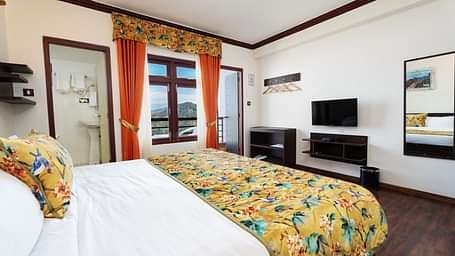 Image of a room with bed and a television in front at Summit Sherpa Mountain Hotel & Spa, Kalimpong
