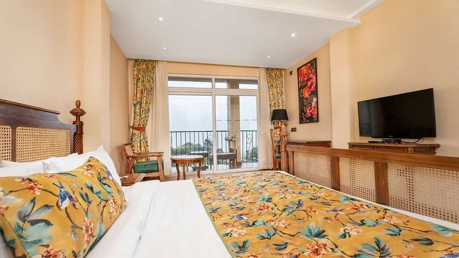 A room at Summit Barsana Resort & Spa, Kalimpong with a double bed, a television and large windows