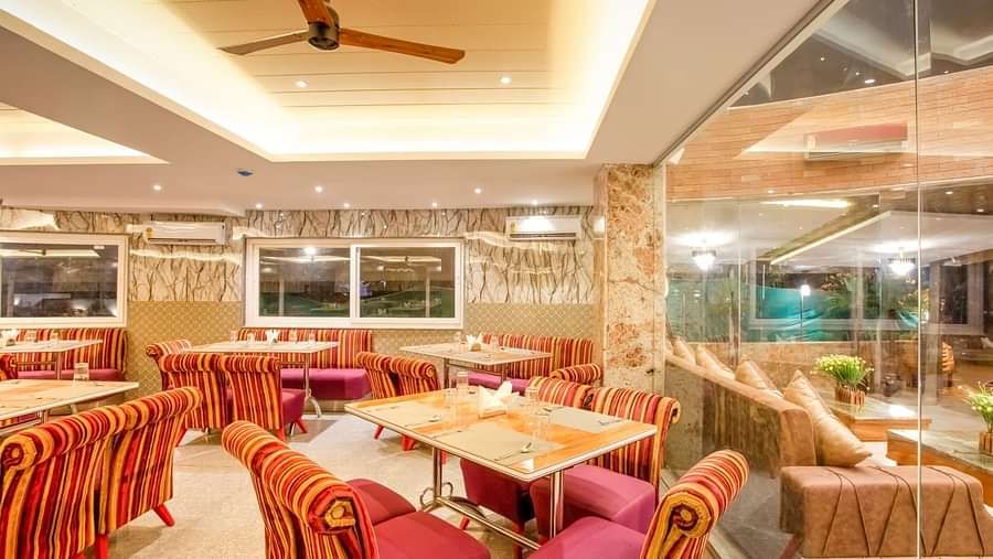  Dining area with cushioned sofas surrounding the table on all four sides, and ceiling fans installed above for added comfort