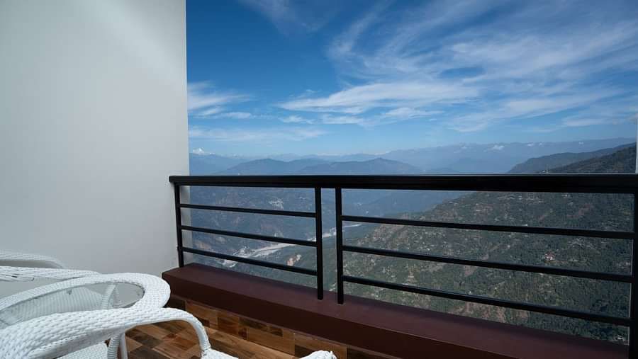 Image of a balcony with seating area and view of the mountians in front at Summit Sherpa Mountain Hotel & Spa, Kalimpong