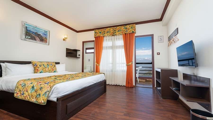 Image of a room with large bed and television in front at Summit Sherpa Mountain Hotel & Spa, Kalimpong