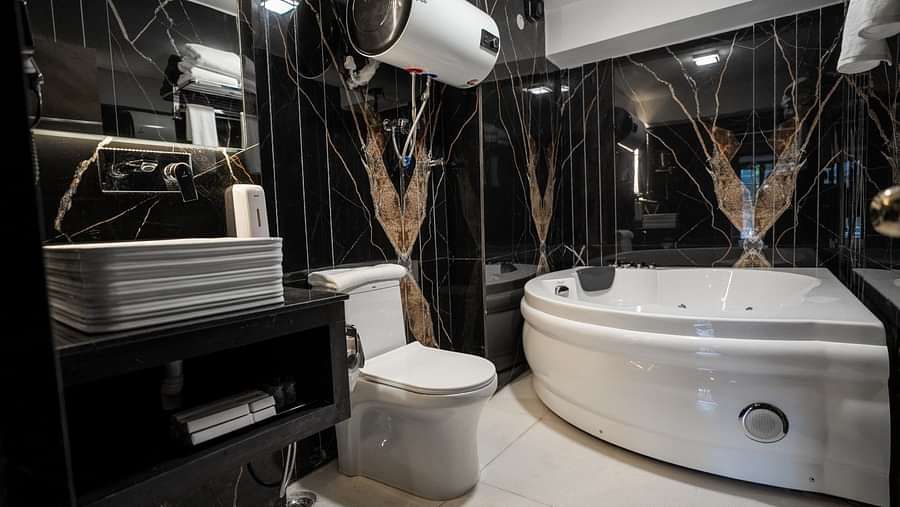 A sot of the well equipped bathroom featuring a jacuzzi, geyser and other ammenities. 