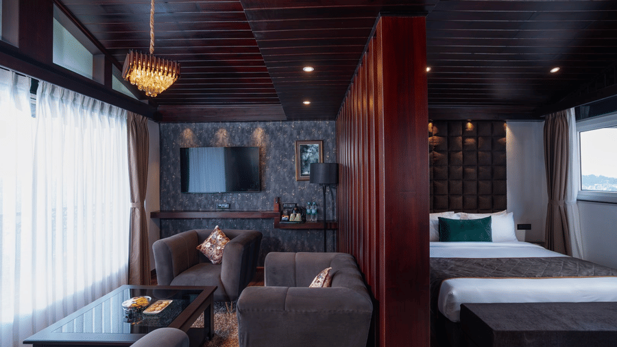 Suite interior at The West Gate Posada By Summit, Darjeeling, with a living space containing armchairs and a table adjacent to a bedroom area.