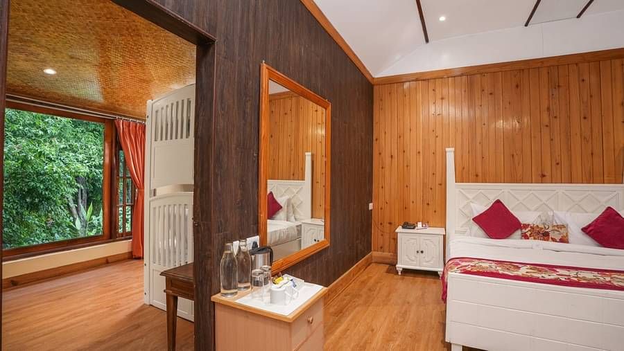 A room at Summit Barsana Resort & Spa, Kalimpong wih a double bed, a large window and wooden panelling
