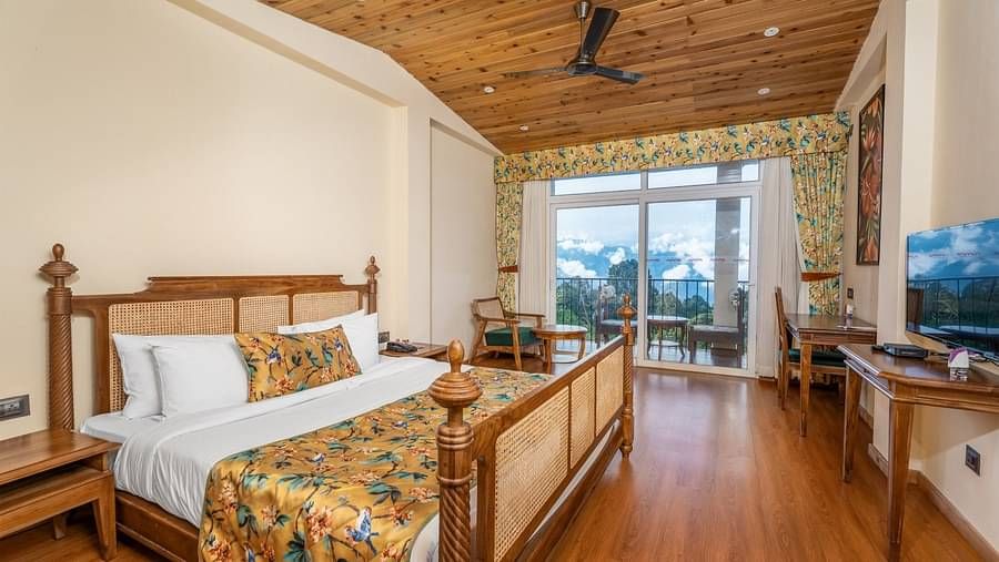 A room at Summit Barsana Resort & Spa, Kalimpong with a double bed, a television and large windows