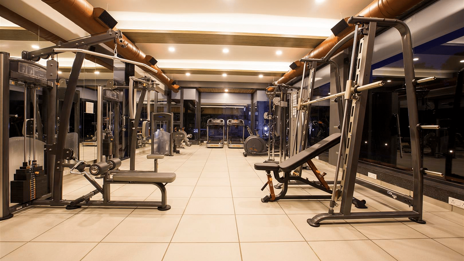An image of a gymnasium with various equipment including cardio machine, treadmill, push-up  bench and a lot more - Kamats India