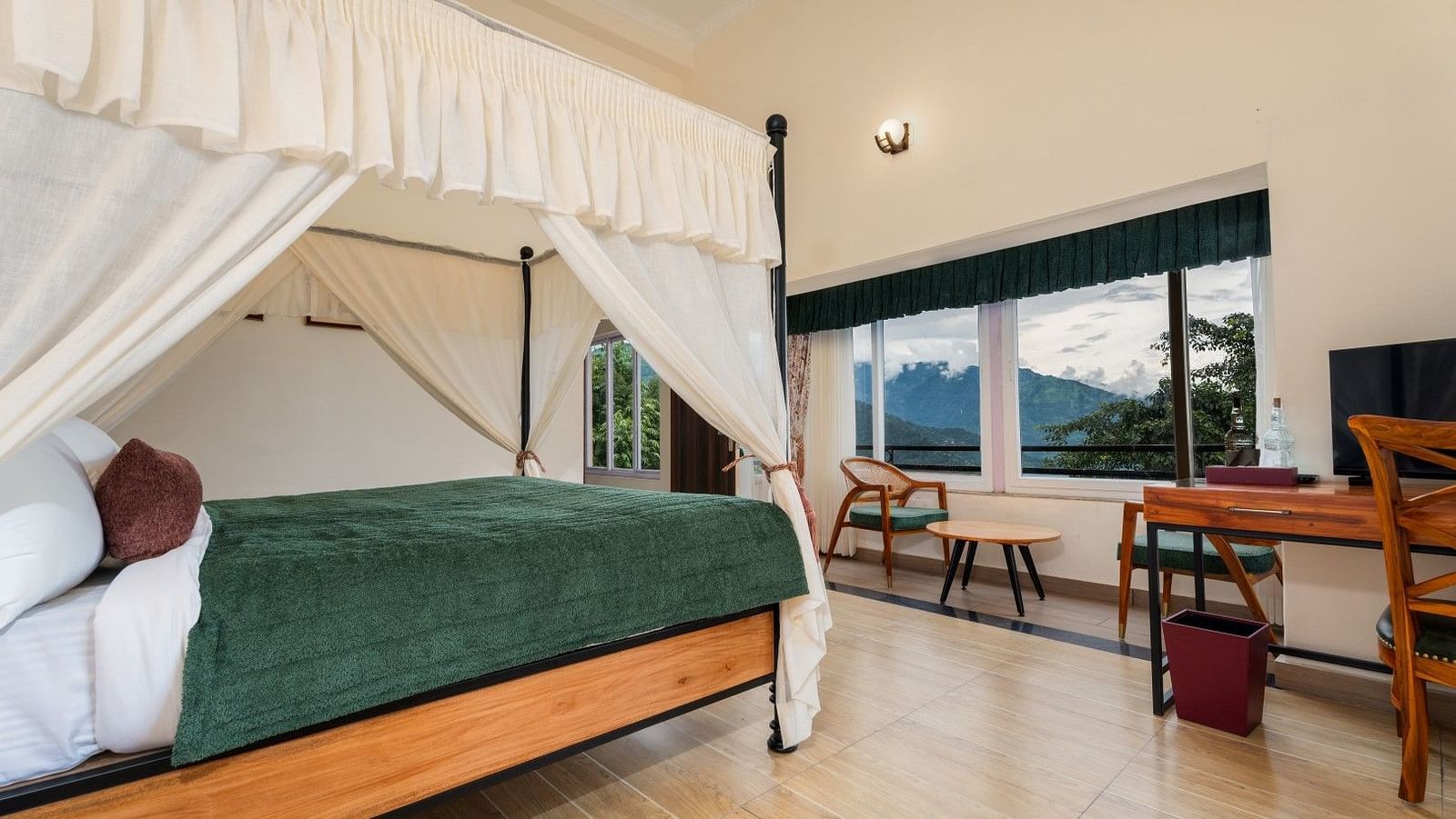 Premium Suite with Balcony features a large windows along with generously sized bed with well-lit illumination, accompanied by wooden furniture