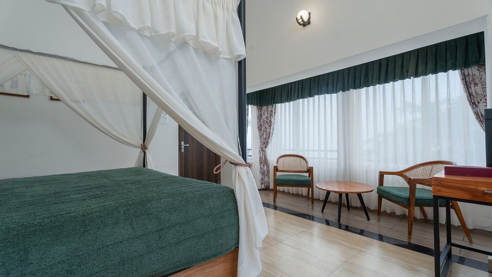 Premium Suite with Balcony features generously sized bed with well-lit illumination, accompanied by wooden furniture
