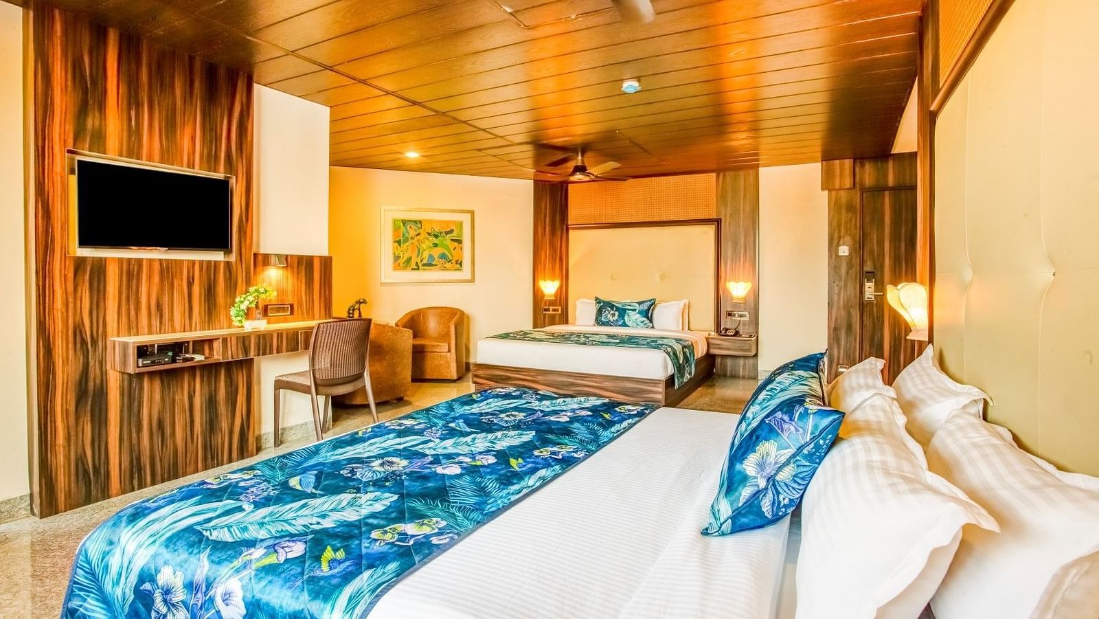 Spacious bed accompanied by a wooden side table, a wall-mounted television, and a wooden console positioned beneath it