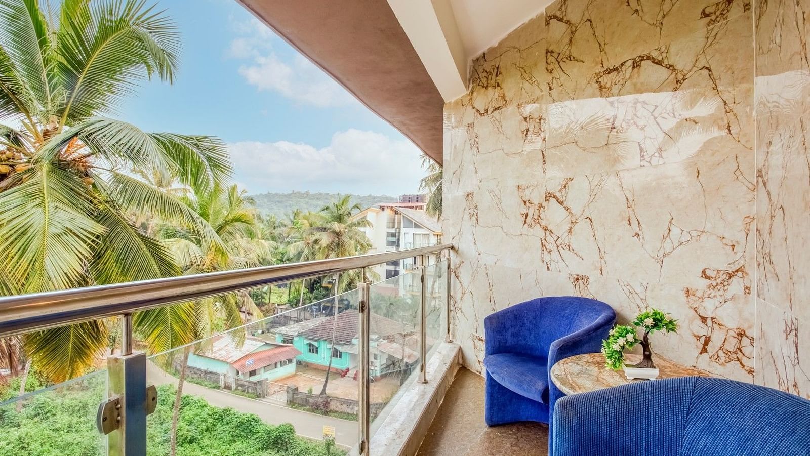 Balcony featuring two cushioned sofas and offering a view of the coconut trees