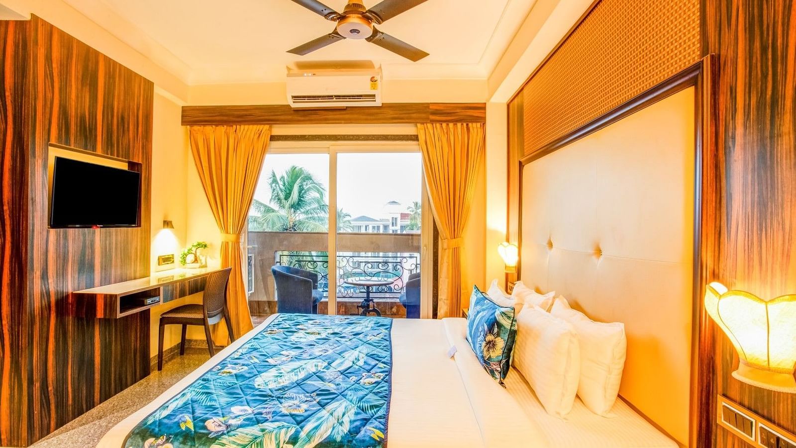Side view of the neatly arranged bed, complemented by a wall-mounted television and a large window, with the curtains gracefully drawn to one side