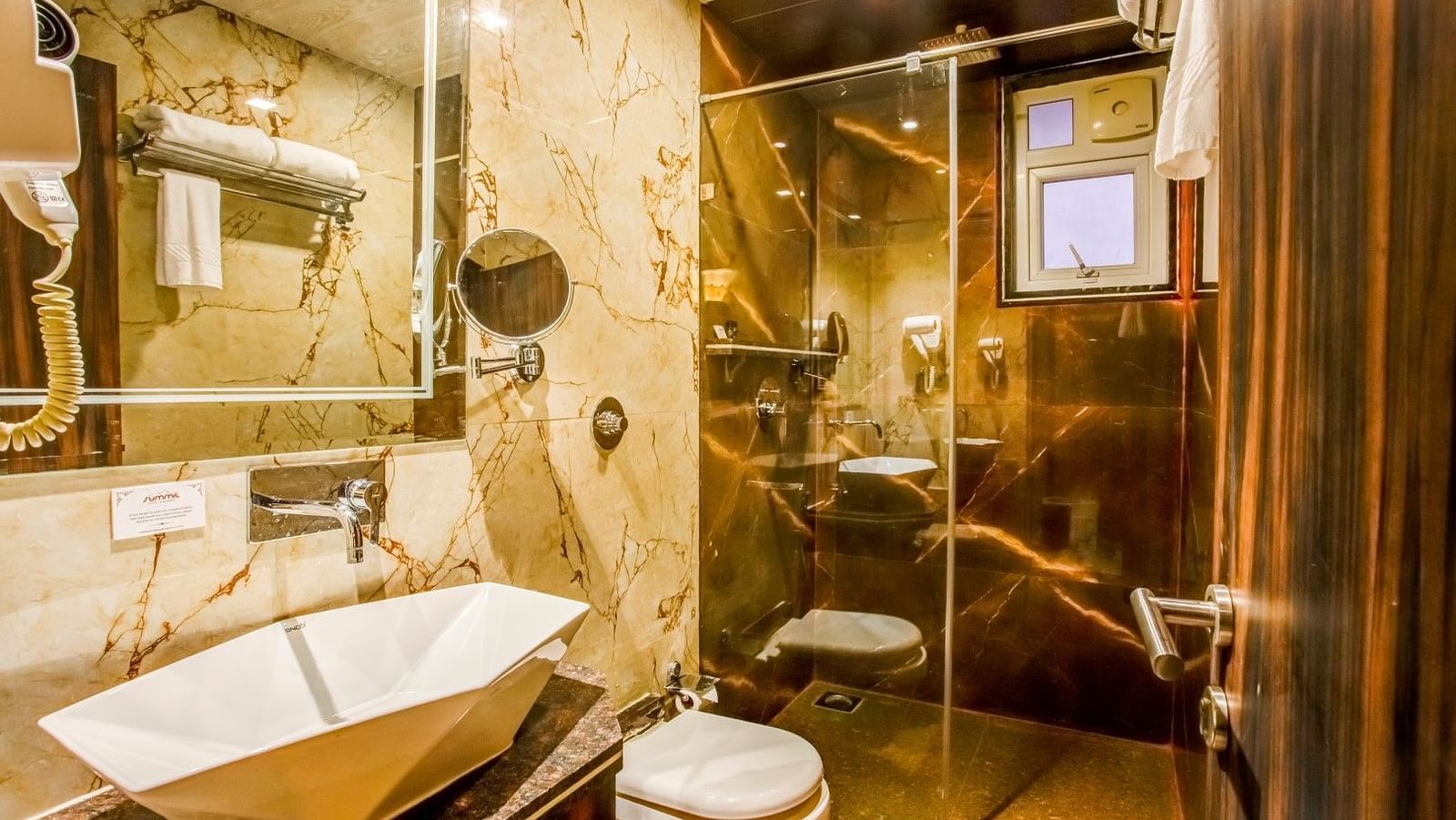  Expansive bathroom featuring a glass partition separating the shower area, an elegant washbasin, and a mirror mounted above it