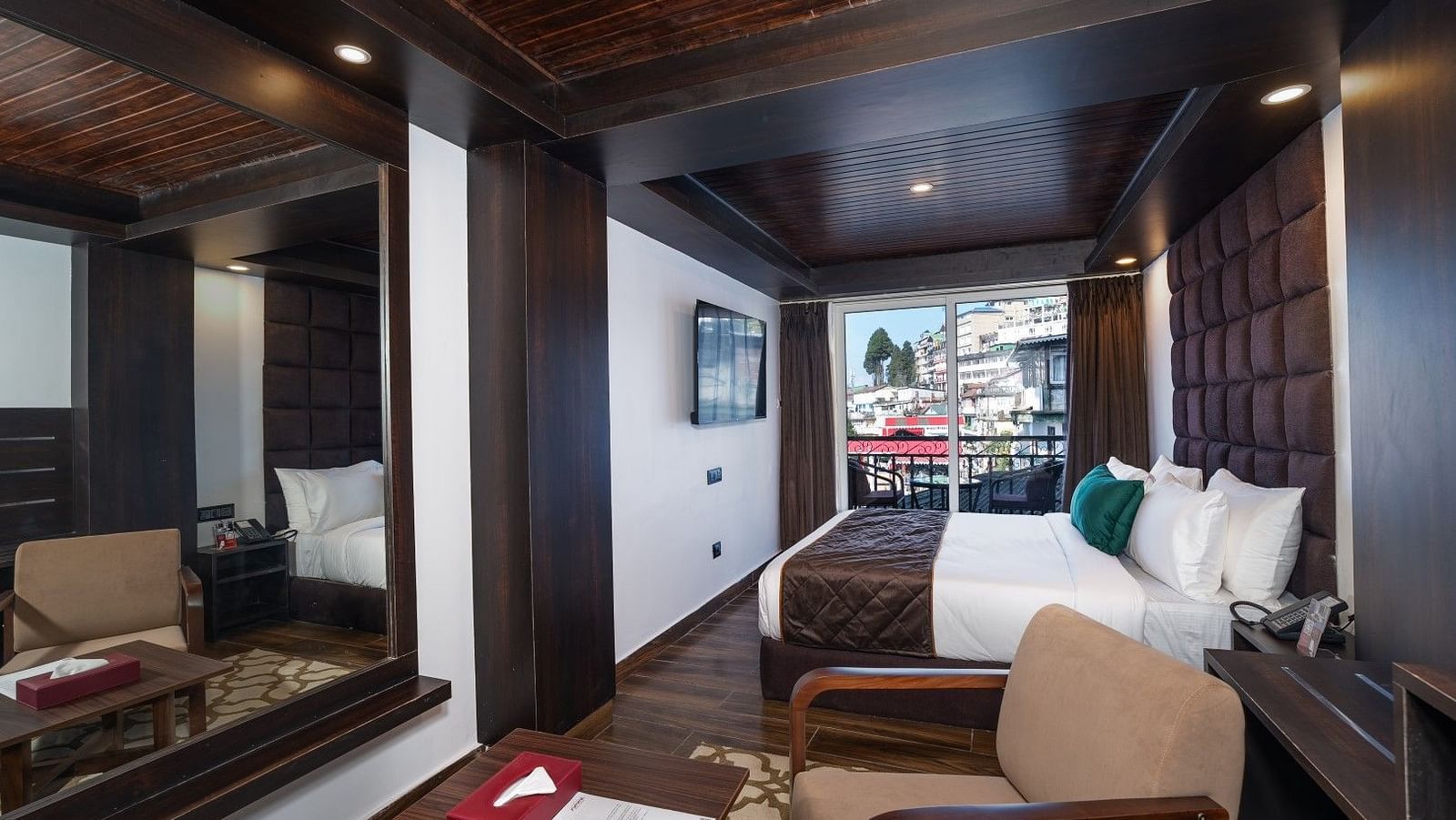 A side-angle view of the room highlighting the bed and LED TV, with a glimpse of the private balcony.