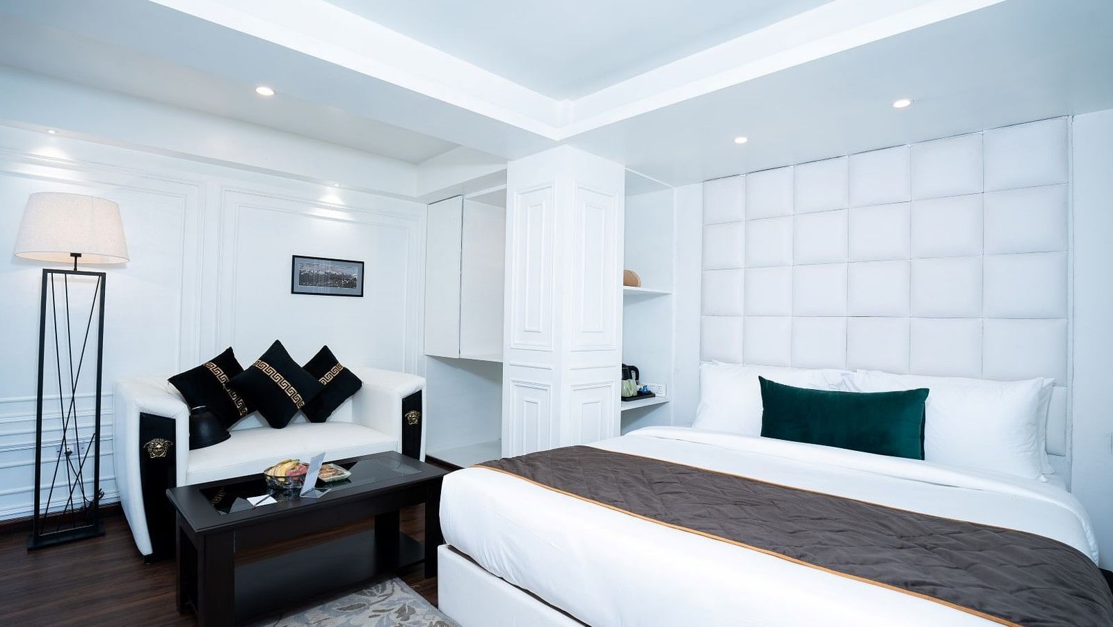 A shot of the room featuring a king-size bed with crisp white linens, ambient lighting, and a sofa with a side table.