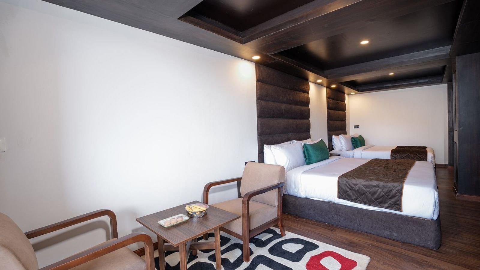 Image of a room with two twin beds and a seating arrangement with two sofas and a small tea table.