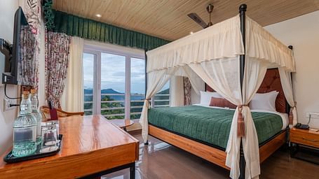 A spacious bed with ample lighting, complemented by wooden furniture