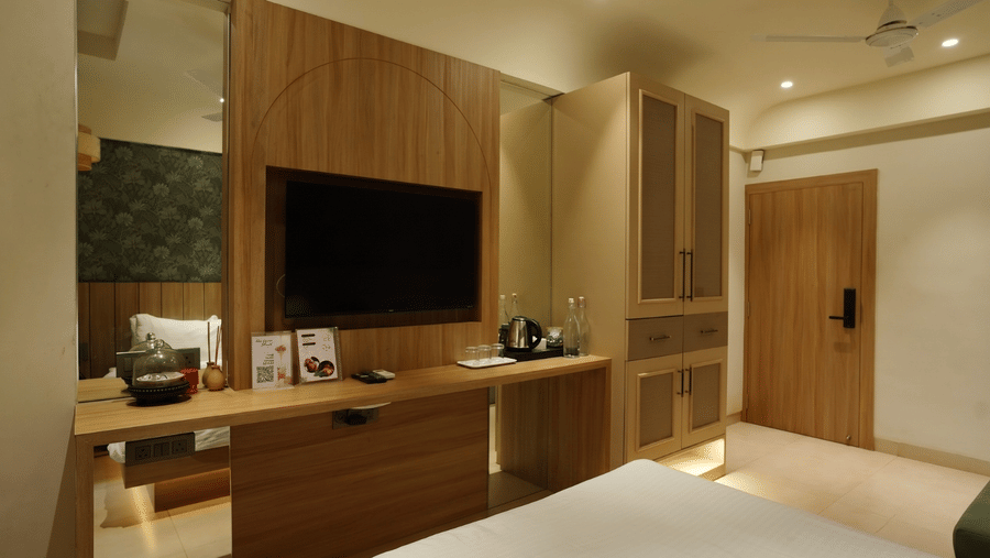 A room featuring wall mounted television, a wooden wardrobe, and a mirror at Bougainvillea, Alibaug.