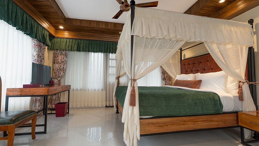 A spacious bed with ample lighting, complemented by wooden furniture.