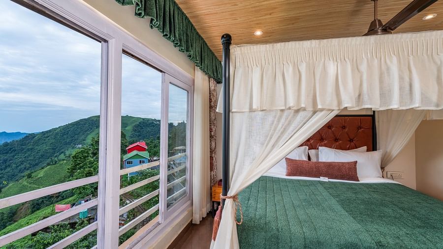 A room featuring a large floor-to-ceiling window that offers a view of the mountains, complemented by a generously sized bed