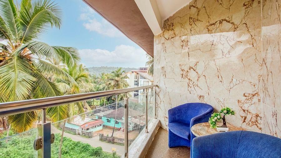  Balcony with a two-seater cushioned sofa and a table positioned in the centre, offering a view of the coconut trees