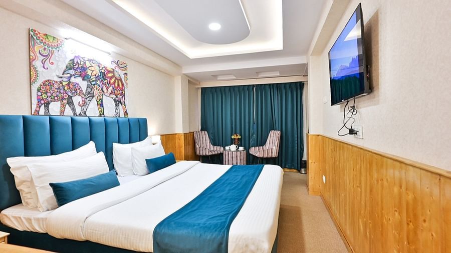A modern and well-furnished hotel room with a comfortable bed, a flat-screen TV, and a seating area.