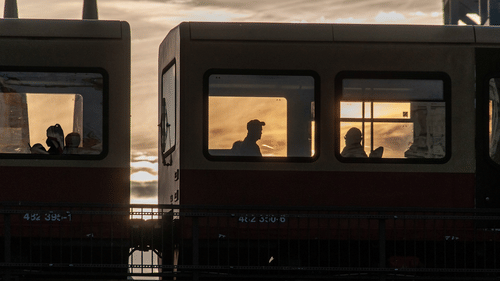 Exterior view of a train bogie and people sitting inside it.
