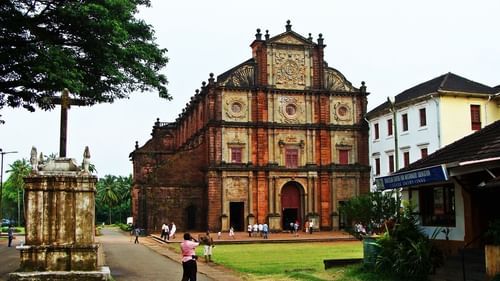 The exterior of the Basilica of Bom Jesus with a manicured garden in front of it, a must visit on your Bengaluru to Goa Road Trip