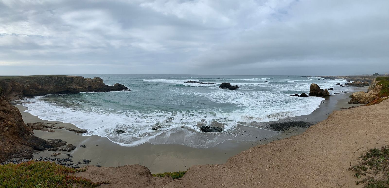 An image of a beach side filled with rocks which are getting hit by ocean waters