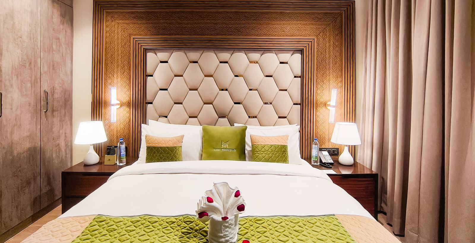 Junior Suite bedroom at The Meriton, New Delhi featuring plush bedding and warm lighting