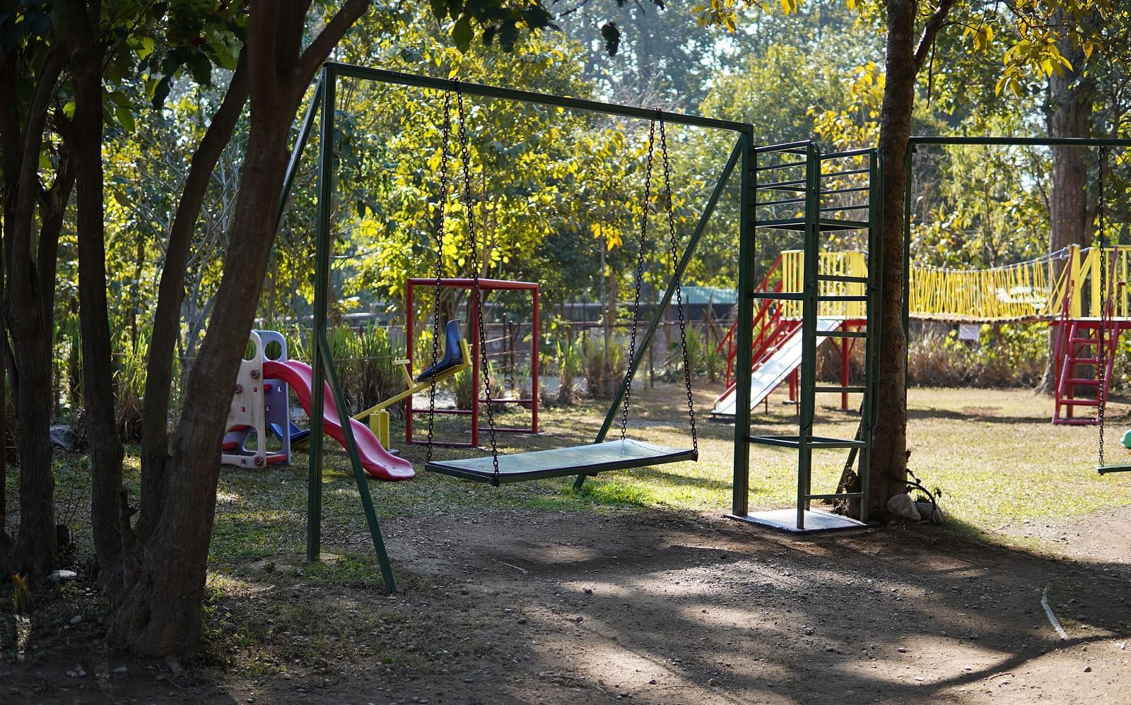 A swing in the Kids Play Area at Saraca Resort & Spa Corbett with trees in the backdrop
