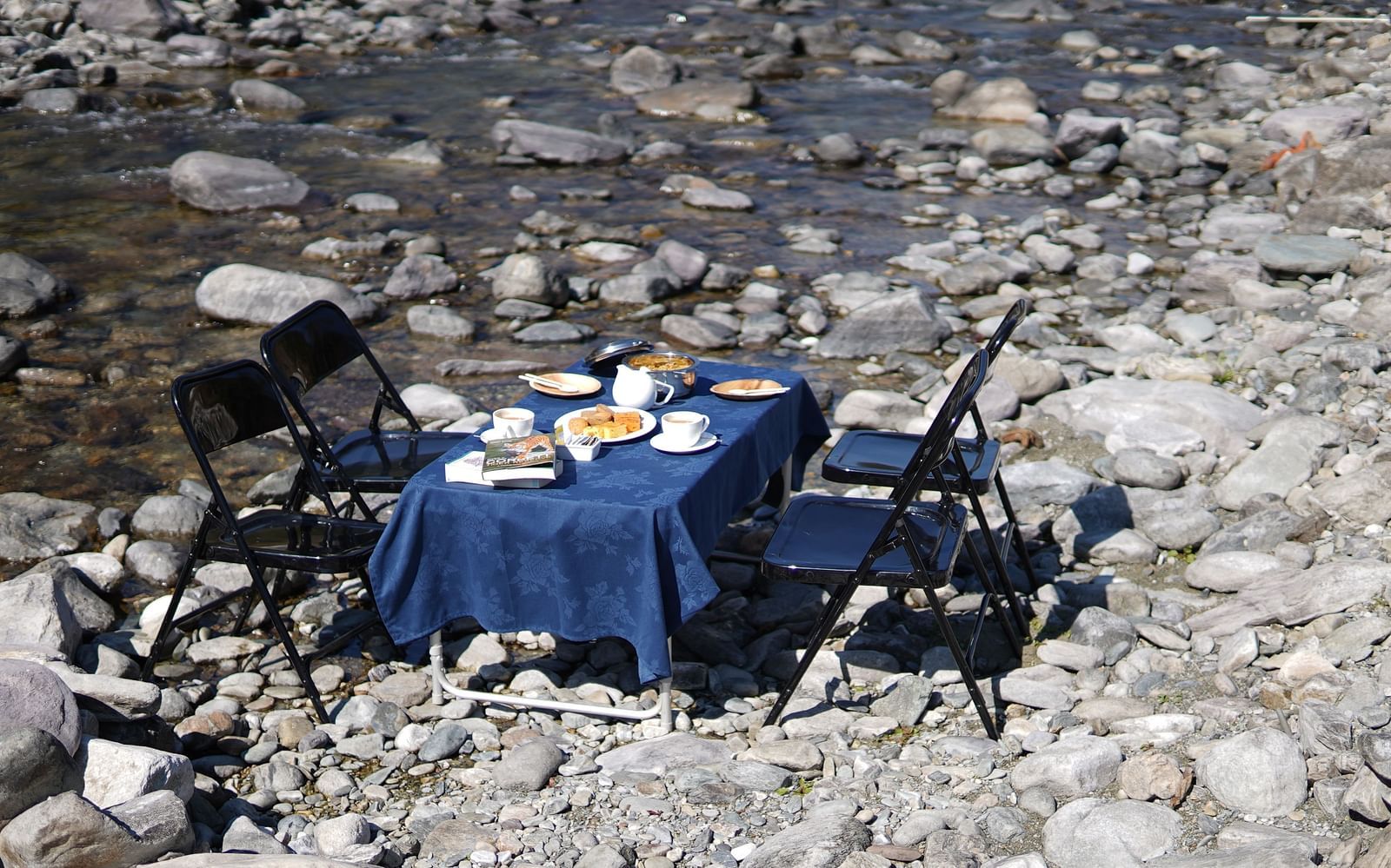 A breakfast table placed right besides a stream of water during the day