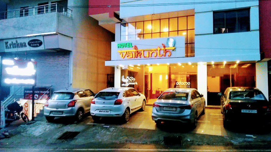Nighttime exterior view of the illuminated hotel building with parked cars along the front entrance.