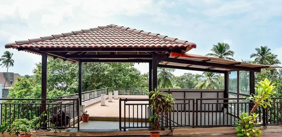 Covered outdoor seating area near a pool at La Vida Studio Inn Goa.