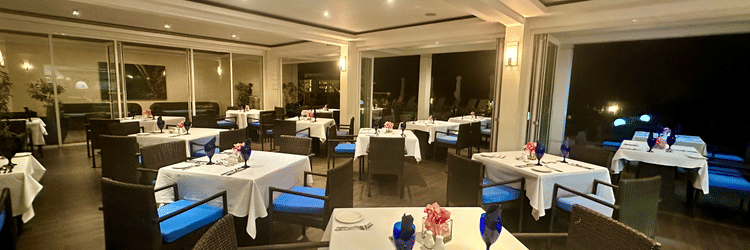 Modern indoor dining area at The Soco Hotel featuring neatly arranged tables, blue chairs, and overhead ceiling lights.