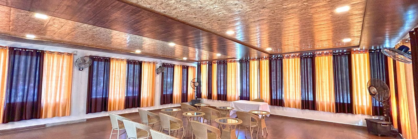 A conference hall with ambient lighting and chairs facing the stage at DLS MJ River Resort, Rishikesh.