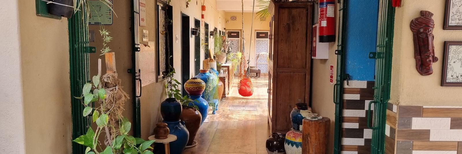 The corridor at the Dream Vision Guest House in Diu surrounded with plants and doors opening to the rooms.
