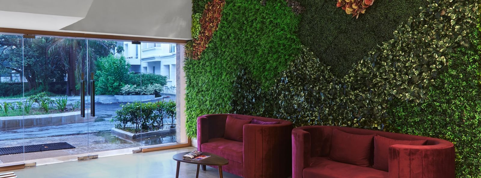 The main entrance and reception area of Monday Hotels Mahape, Navi Mumbai, with a vertical garden and contemporary furniture.