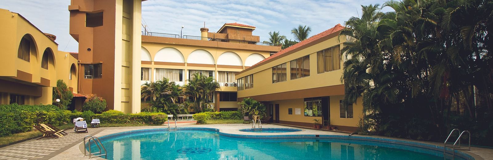 A view of the outdoor swimming pool at Paradise Isle Beach Resort, Udupi with the resort in the backdrop during the day