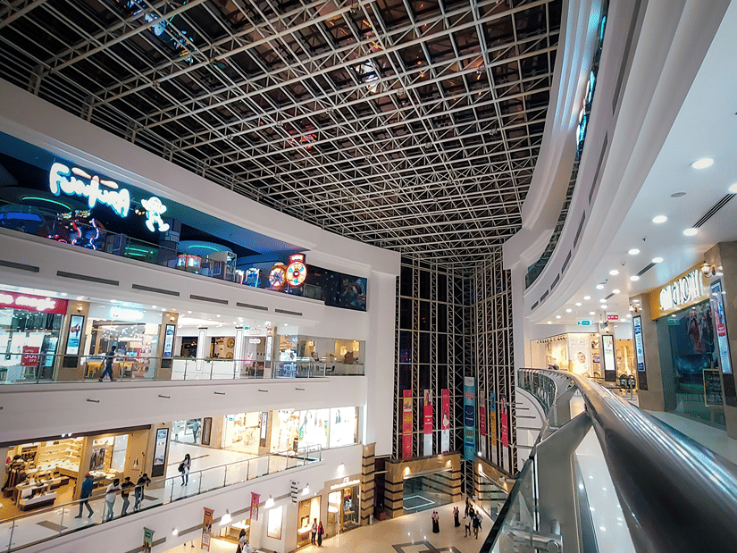 Interiors of a shopping mall featuring patterned ceiling and people walking around on multiple floors