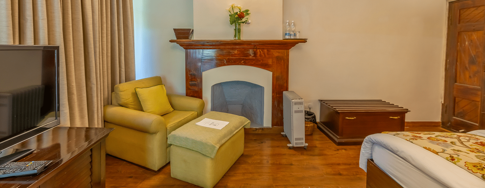 A deluxe room with a fireplace, a seating area, flat TV screen, and a cabinet at Bedzzz Xclusiv Baikunth, Manali