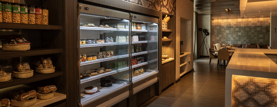 View of the grab-and-go station, showing shelves filled with a variety of snacks, drinks, and fresh food at The Residency Towers Rameswaram.