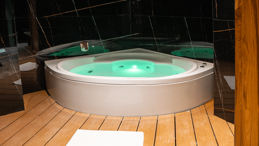 A jacuzzi with bubbling water placed in a wooden deck enclosure at Infiniti Hotel, Indore.