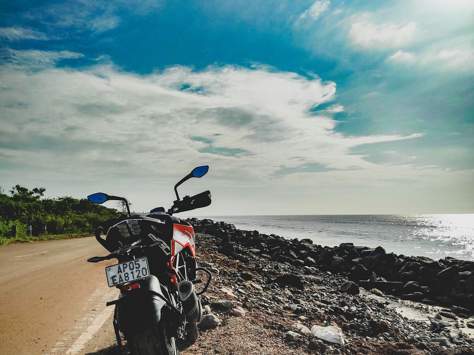a motorcycle parked on the side of a road near the ocean