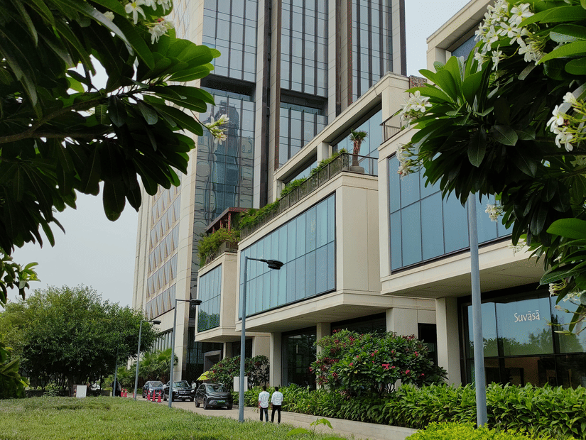 A view of tall glass buildings in a cyber park with lush greenery surrounding them.