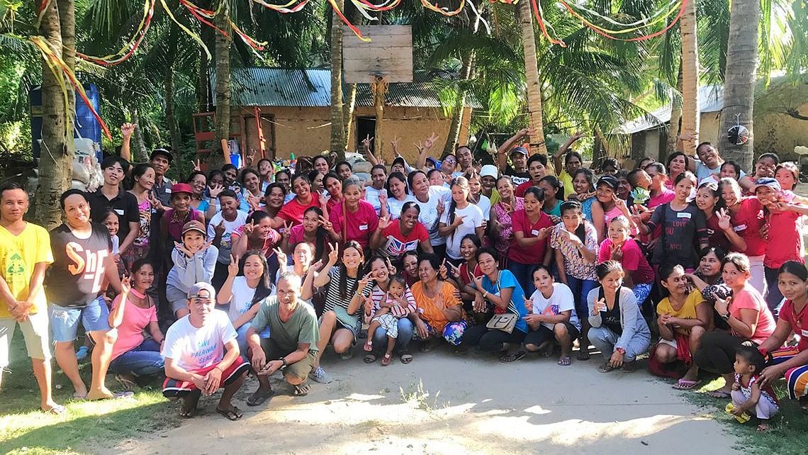 Large group of people seated outdoors under trees for a group photo at Flower Island Resort.